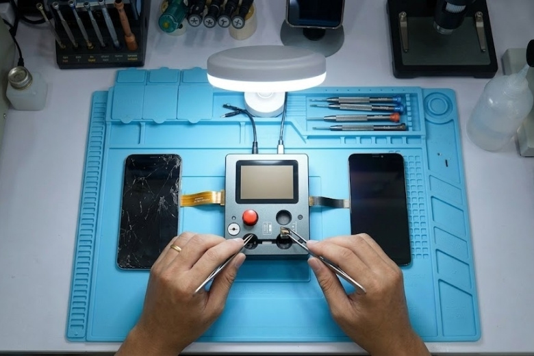 Thay màn hình Dura iPhone 15 Plus 2 Kỹ thuật viên sử dụng box lập trình để nạp mã True Tone từ màn hình iPhone 15 Plus cũ sang mới.